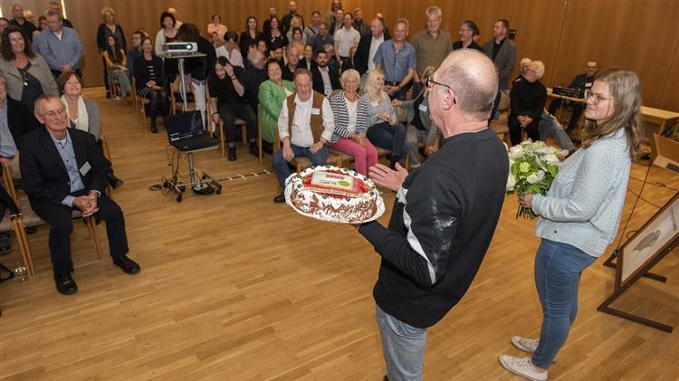 Manfred Gesch und Malina Zelezny überreichen die Torte im Namen der AG Prophylaxe
